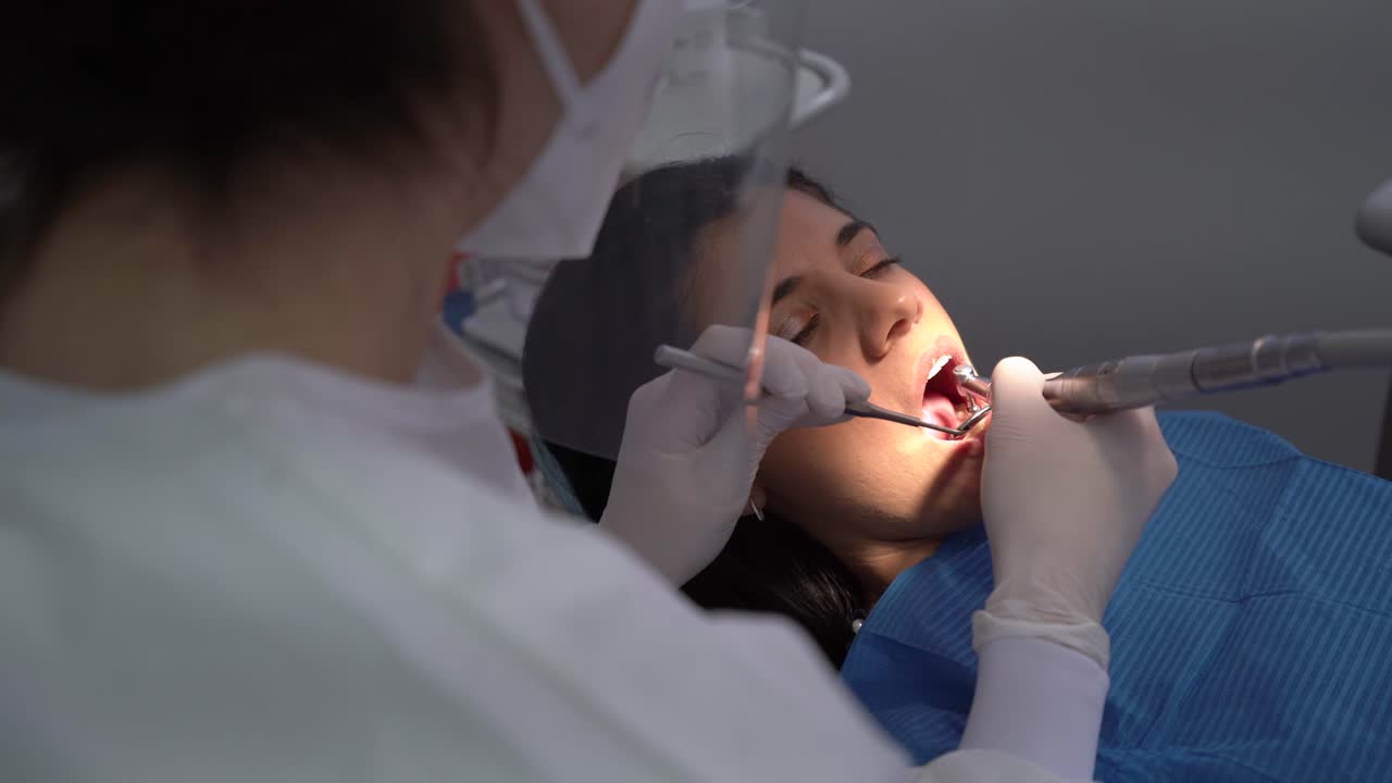 dentista de cultivos curando el diente de una paciente femenina