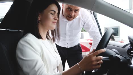 a young family with children inspecting a new car and talking to a dealer at a dealership. a husband and wife are looking at a new luxury model of an electric car. technology and people concept