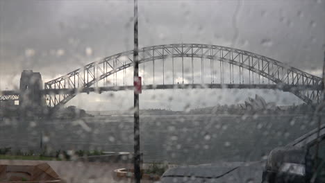 Gotas-De-Lluvia-Golpeando-El-Parabrisas-Desde-El-Interior-De-Un-Automóvil-Con-El-Puerto-De-Sydney-En-El-Fondo