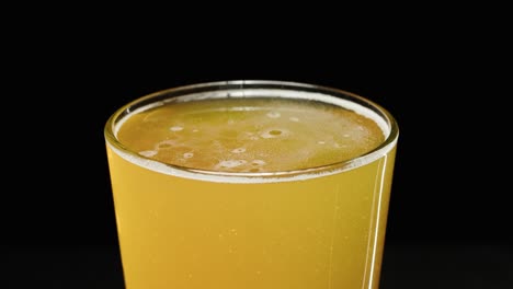 Vista-Superior-De-La-Cerveza-En-Un-Vaso-Frío-Que-Muestra-El-Sedimento-Y-Las-Burbujas-De-Una-Cerveza-Artesanal-Ipa-Nebulosa,-Vista-Superior-De-Fondo-Negro