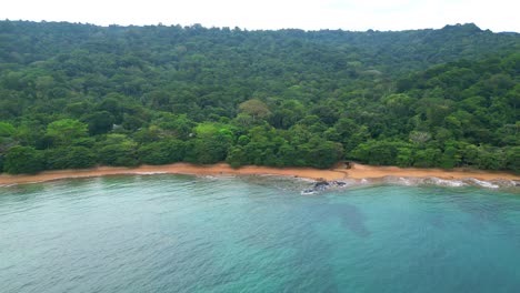 Volando-Hacia-Atrás-Sobre-El-Mar-Con-Vistas-A-La-Playa-Sundy-Con-El-Bosque-Que-Cubre-La-Playa-HBD-Sundy-Lodge,-El-Lugar-Más-Caro-De-La-Isla,-En-Prince-Island,-África