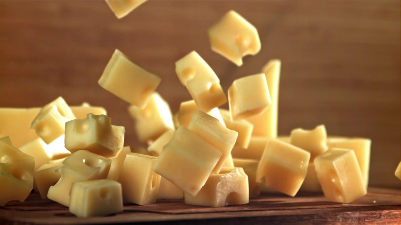 Ralenti de dés de fromage tombant sur une planche en bois