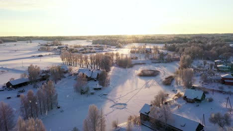 bright sunset over rural village during light snowfall, aerial view