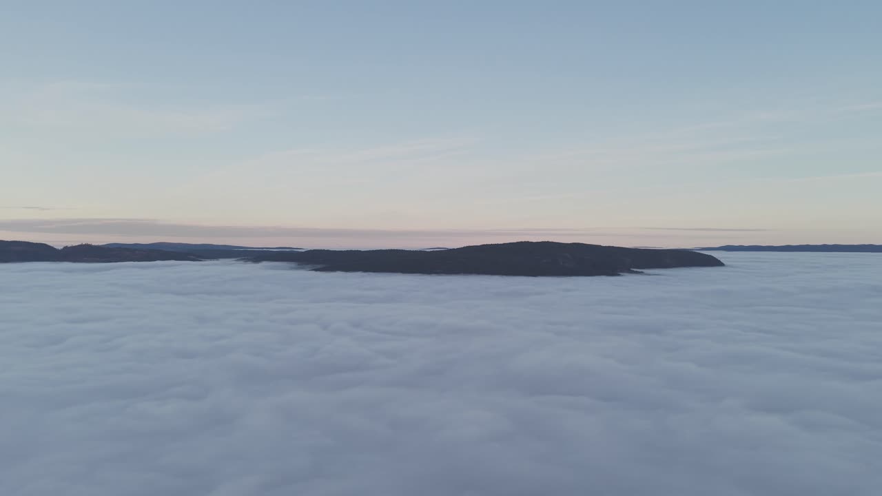 Mountain peaks sticking out of clods in valley. Drone footage