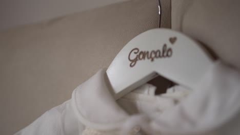 delicate white baby outfit hanging on a personalized hanger