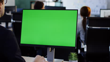 vista trasera del hombre de negocios que trabaja en la computadora y escribe en el teclado en la oficina