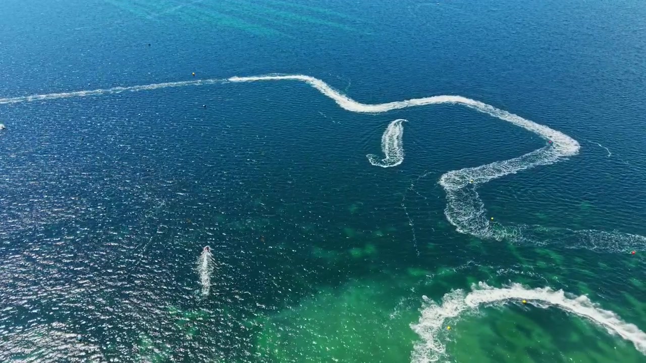 Berrak sularda, birçok yarışçının dalgalar arasında hızla ilerlediği bir jet ski yarışı yapılıyor.