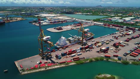 puerto de contenedores de envío, dos grúas y un pequeño barco atracado, día soleado en curacao