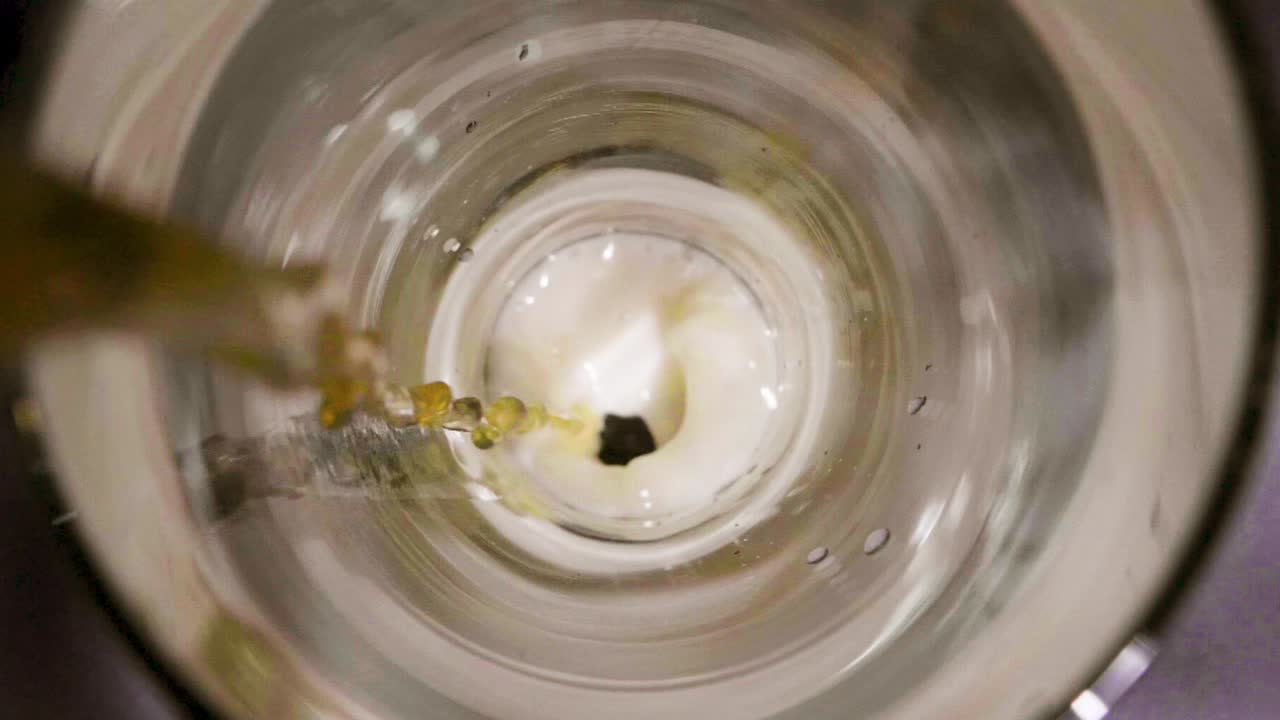 Birra versata in un bicchiere con schiuma che emerge.
