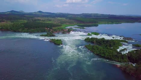 Aerial view capturing the dynamic whitewater rapids of the Nile River near Jinja, Uganda, flowing vigorously through a landscape rich with lush green vegetation and rolling hills, drone dolly in shot