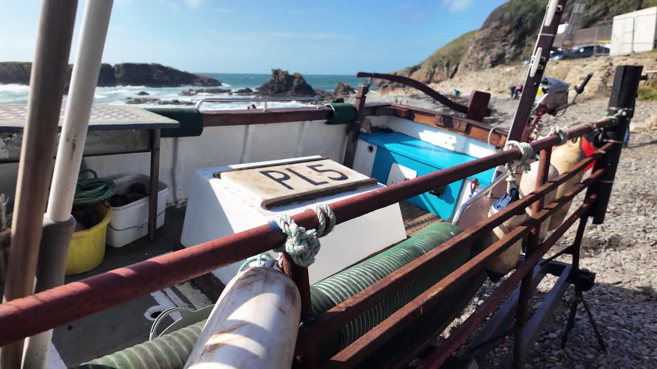 Fishing boat with equipment and trailer on beach by rugged ocean coast