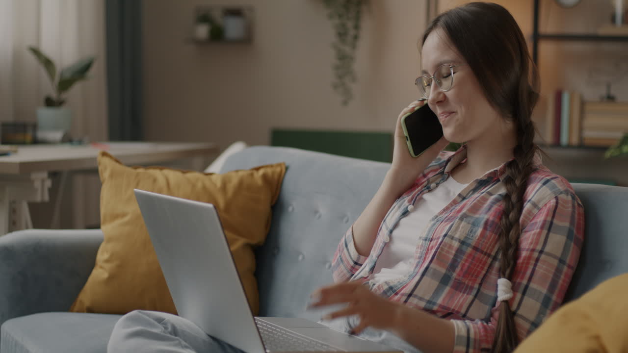 mujer trabajando desde casa en una computadora portátil y una llamada telefónica