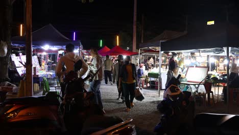 personas navegando por los puestos en un mercado nocturno al aire libre