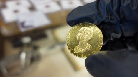 coleccionista examinando la antigua moneda de oro portuguesa