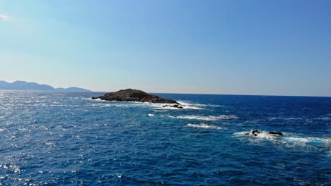 blue ocean in small bay with rocky cliffs at jerusalem beach, greece - aerial pullback