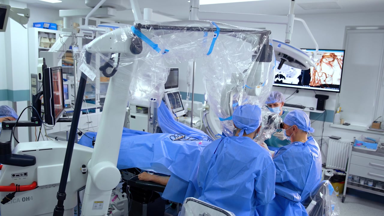 Patient undergoing neurosurgical operation in modern operating room. Doctors use powerful microscope at surgery.