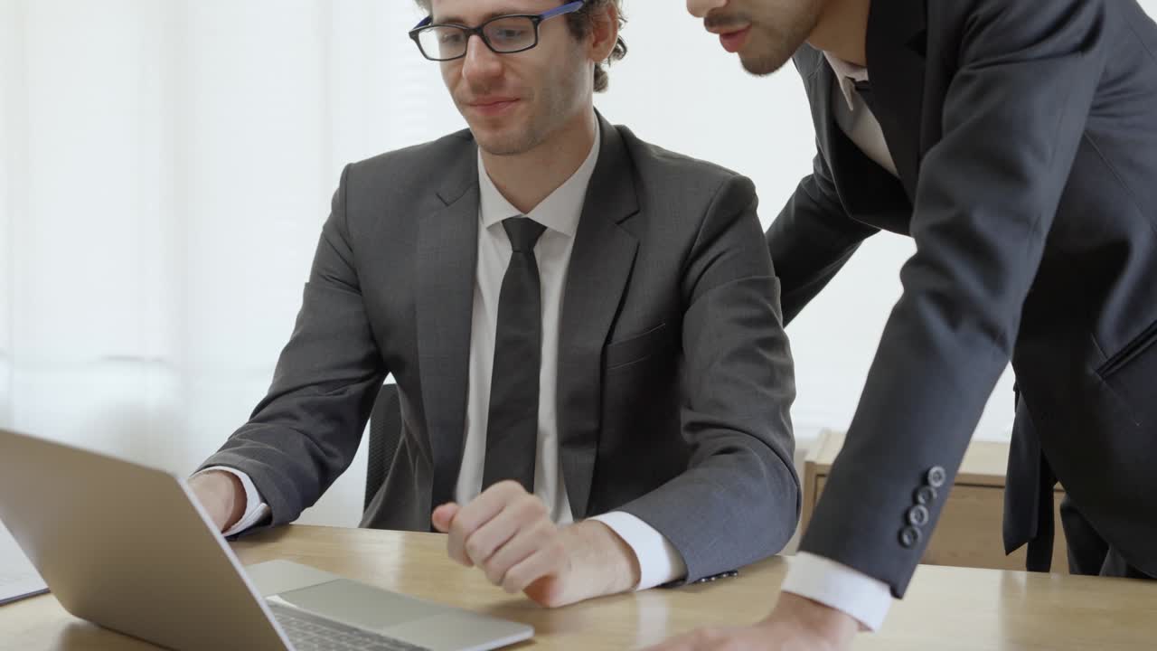 Uomo d'affari che consulta i bilanci su un computer portatile. Il dirigente sta spiegando i dettagli commerciali al proprietario dell'azienda.