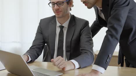 hombre de negocios que consulta los estados financieros en una computadora portátil. el ejecutivo está explicando los detalles del negocio al propietario del negocio.