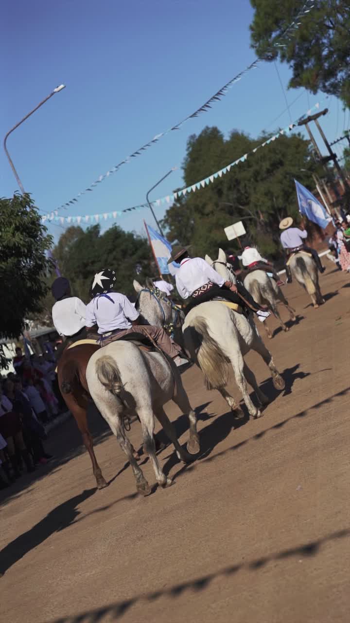 Horseback riders participate in a traditional parade, celebrating cultural heritage with an argentine flag visible in the background in slow motion