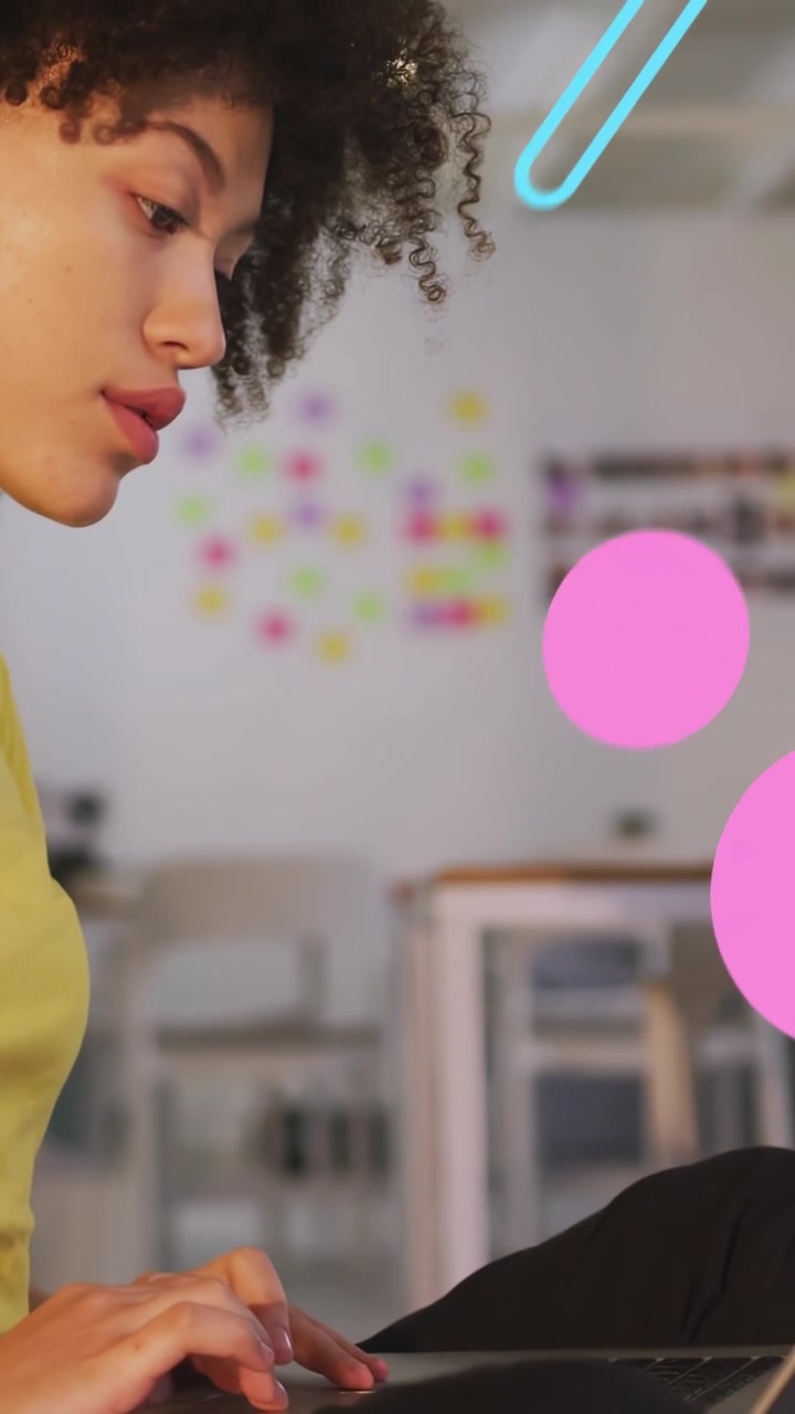 Video verticale: Donna che digita su un laptop, con forme al neon che fluttuano intorno al viso, mettendo in pausa e riprendendo il lavoro tecnologico