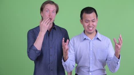 두 명의 사업가가 녹색 스튜디오 배경에 충격적인 나쁜 소식을 받고 있습니다.