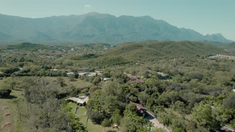 Idyllic-suburbs-with-mountain-landscape-visible-in-distance,-aerial-captured-during-sunshine-day,-location-Santiago,-Nuevo-Leon,-Mexico