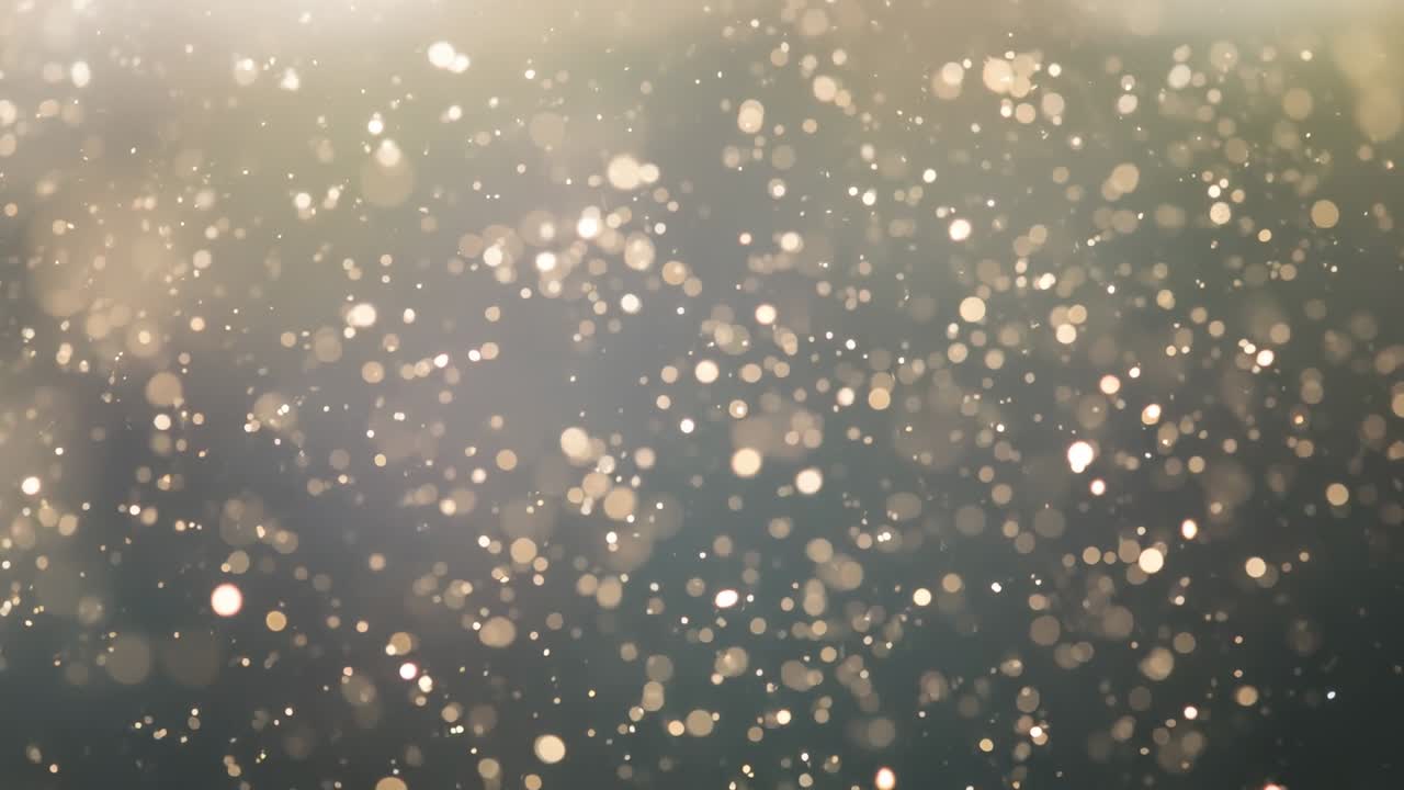 Off-camera light illuminating golden bokeh particles drifting over dark backdrop, density rising