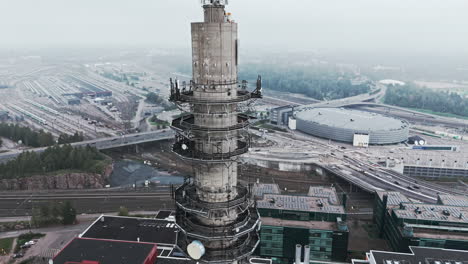 Aerial-medium-shot-of-a-bleak-industrial-concrete-television-and-radio-link-tower-in-Pasila,-Helsinki,-Finland-on-a-bright-and-foggy-day