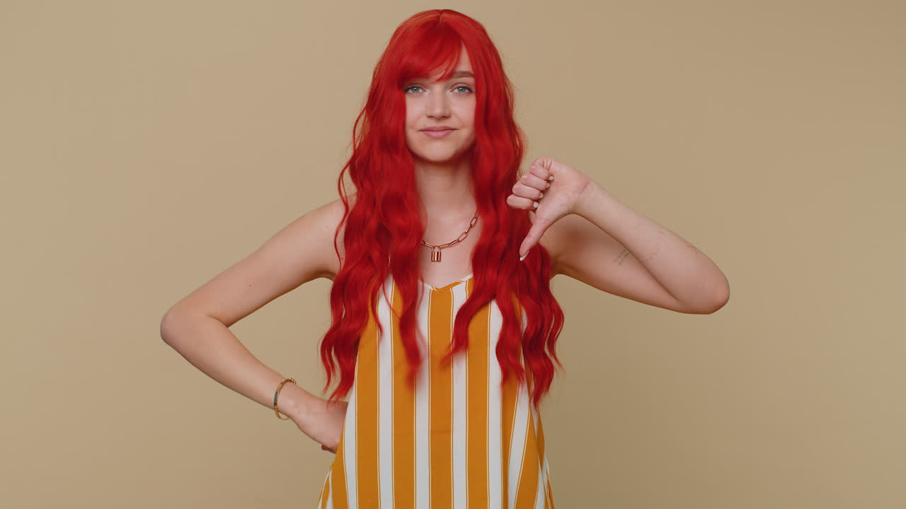 ⁇ 크 트립을 입은 화가 난 여성이 엄지손가락을 아래로 내리며 표시 제스처, 불쾌감, 불만을 나타 ⁇ 니다.