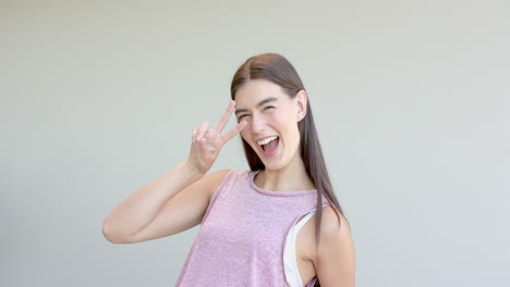 Teenage-Caucasian-girl-with-long-brown-hair-flashes-a-peace-sign-at-home