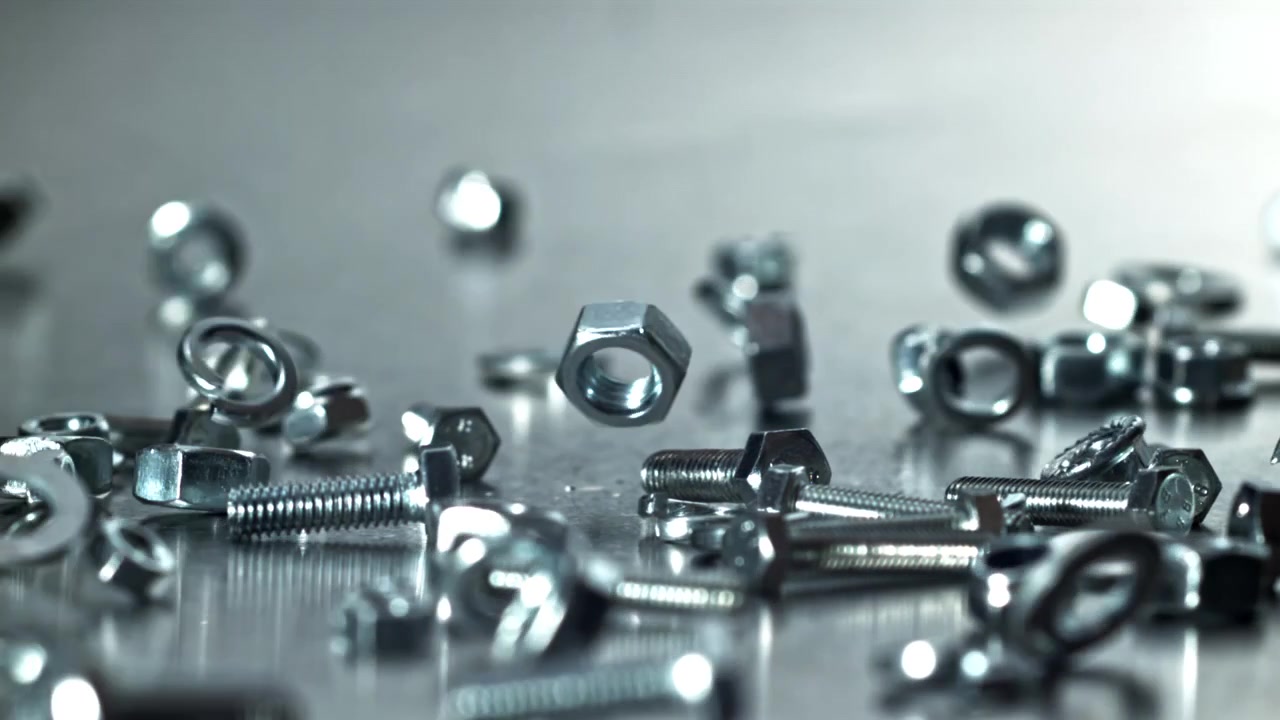 Slowmotion af metalbefæstelser, der falder ned på en metallisk overflade