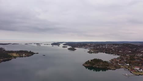 Aerial-from-Grimstad-coastline-looking-towards-North-Sea-and-atlantic-ocean---Cloudy-morning-aerial-Norway-with-houses-and-marina-at-Groos-and-Osterhus-to-the-right