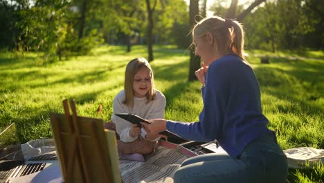 mother and daughter drawing in a park