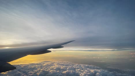 airplane wing view above clouds at sunset or sunrise