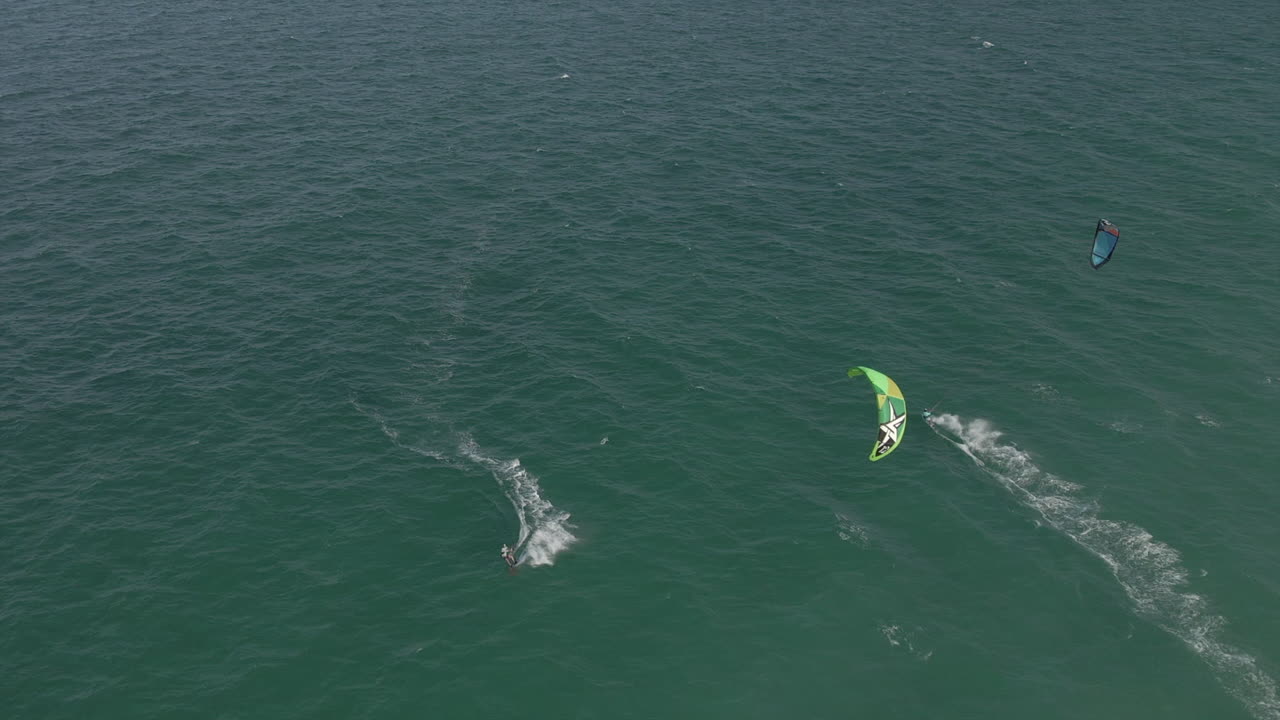 antena: kitesurfistas viajan en direcciones opuestas en el mar verde picado