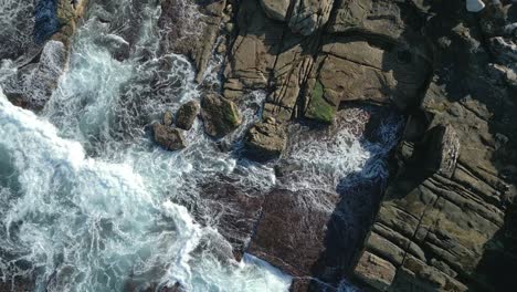 Static-aerial-top-down-waves-crashing-the-rocks-on-the-coast-at-Sydney,-Australia