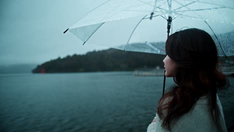 woman with umbrella by the lake in the rain