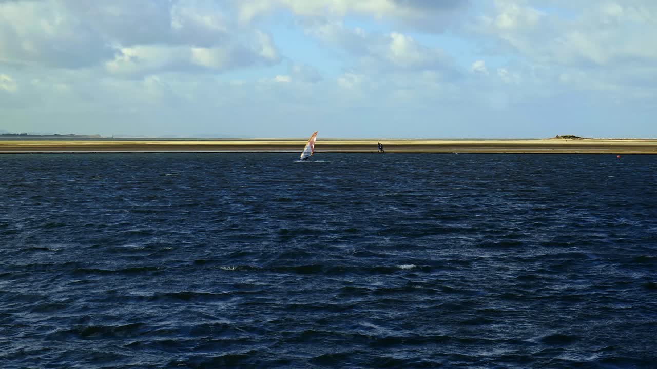 서쪽 커비에 있는 고르지 못한 바다 호수에서 슬로우 모션으로 항해하는 고독한 수상 스포츠 윈드서퍼