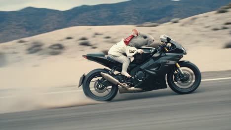 a mouse rides a black motorcycle on a desert road