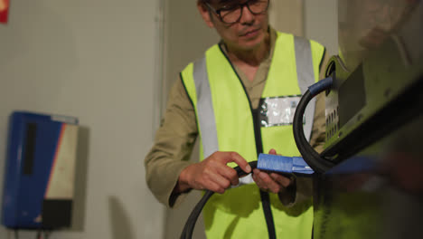 Asian-male-worker-wearing-safety-suit-with-helmet-in-warehouse