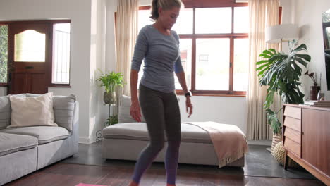 senior woman practicing yoga at home near decorated christmas tree