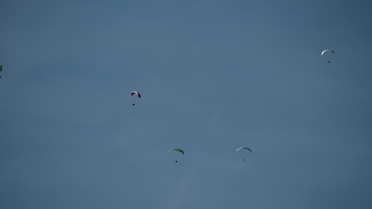 toma amplia que muestra un grupo de parapente volando contra el cielo azul y la luz del sol en el aire
