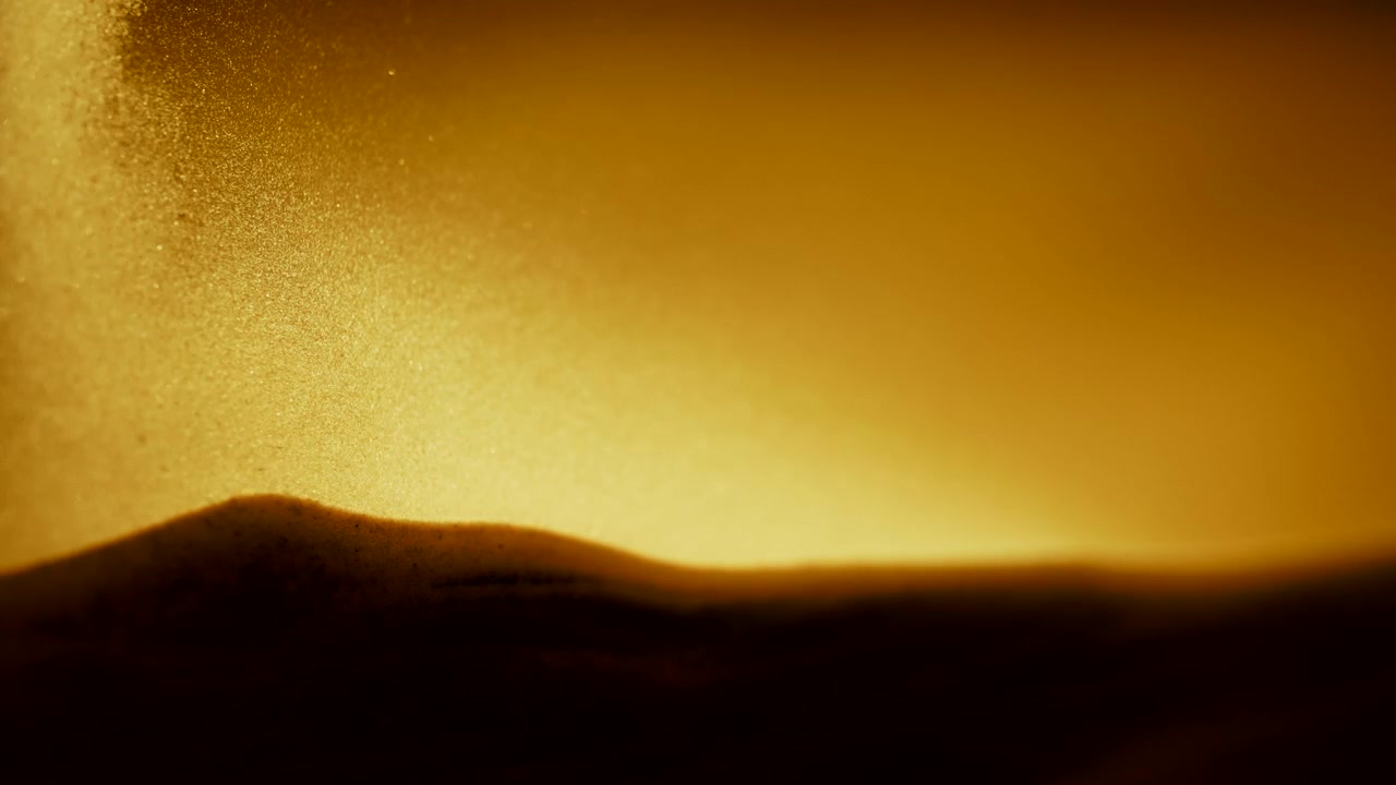 Gule sandkorn, der falder ned på sandbunken i abstrakt slowmotion