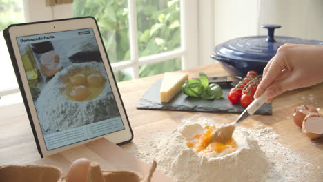 person following pasta recipe using app on digital tablet