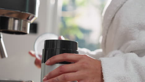 woman opens coffee grinder in kitchen closeup. lady uses modern domestic appliance for energetic beverage making at home. easy and fast cooking