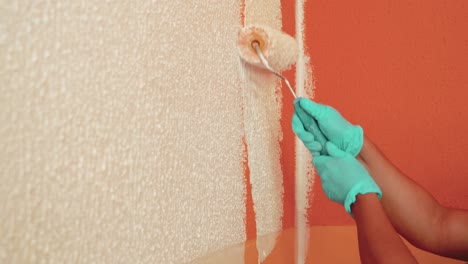 close shot of someone using painting roll to paint wall in white