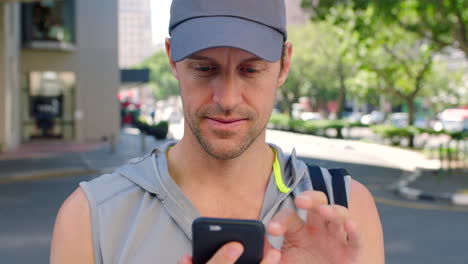 Athlete-using-his-phone-outdoors-in-an-urban-town