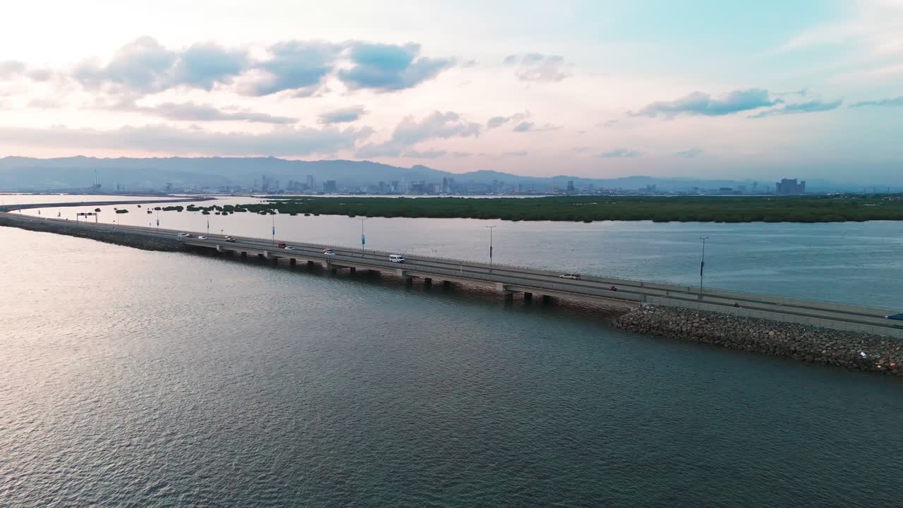 4K cinematic aerial drone shot of a coastal bridge at golden hour, leading toward the city skyline of Cebu, Philippines. A stunning scene symbolizing connection,progress, travel,and modern development