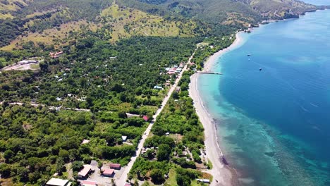 Aerial-drone-landscape-view-of-remote-tropical-Atauro-Island-with-green-trees,-white-beach-and-crystal-clear-ocean-water-of-coastal-community-in-Timor-Leste,-Southeast-Asia