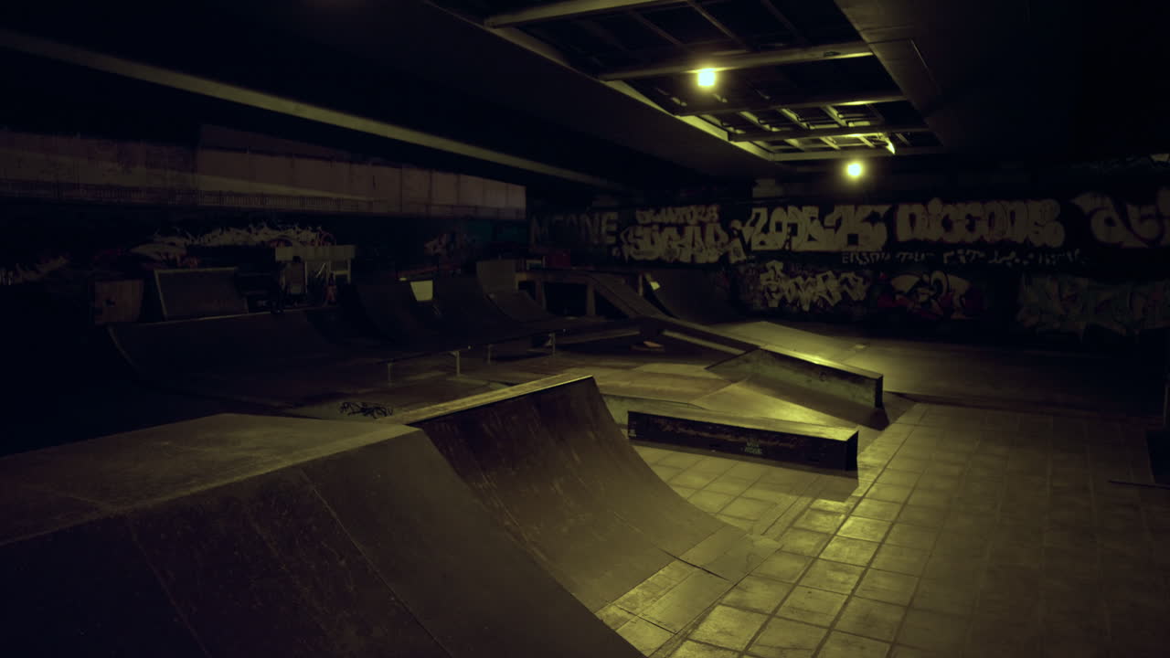 Sporty mand laver farligt trick på BMX-cykel i skatepark om natten